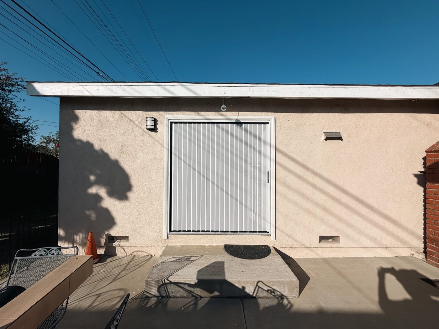White folding screen across a wide door opening on a small garden building