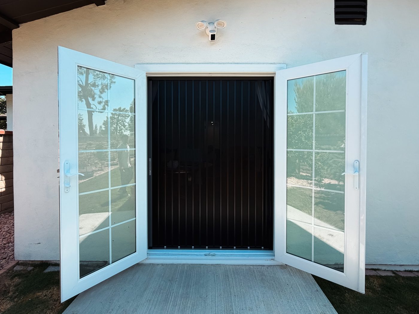 Black folding screen closed between two open white French doors