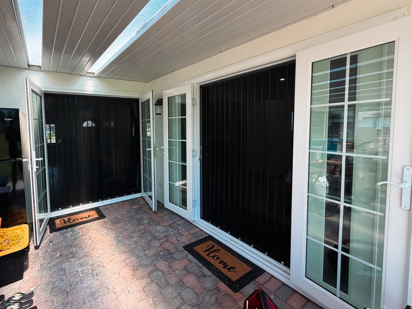 Black folding screens on French doors along a covered patio