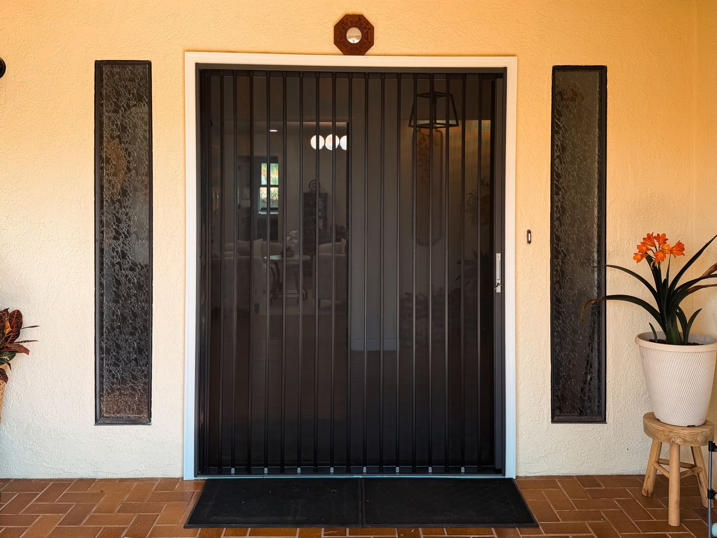 Black folding screen across a front entry with decorative glass sidelights