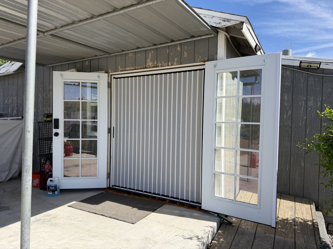 White folding screen between two open French door leaves on a covered patio